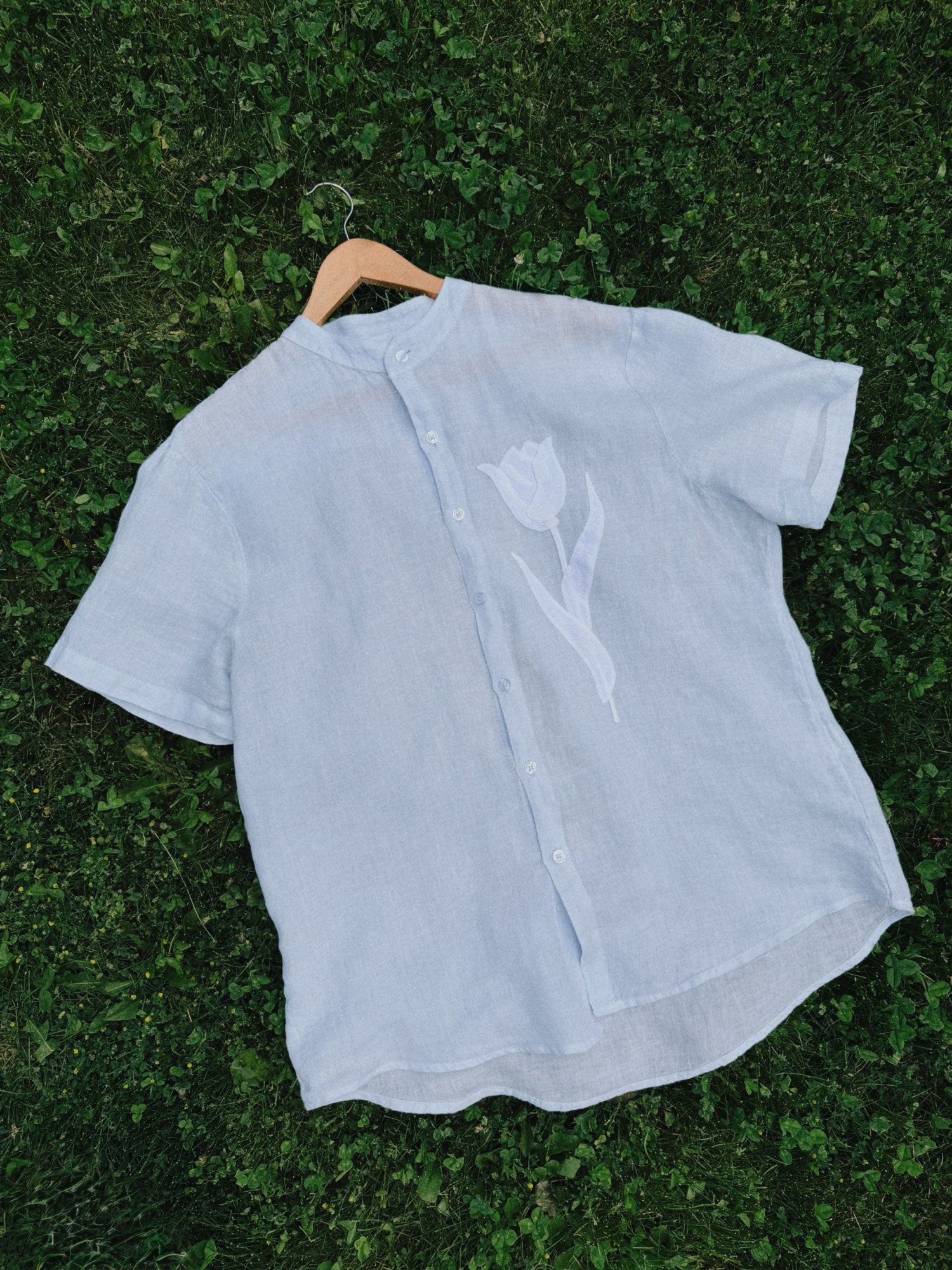 Light blue shirt with a tulip appliqué design on a grass background
